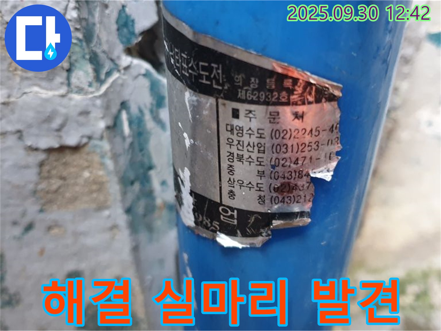 수도 배관에 부착된 오래된 스티커 - 시공 업체 정보와 다양한 연락처가 꼼꼼하게 적혀 있어 누수 해결의 실마리가 될 수 있습니다.