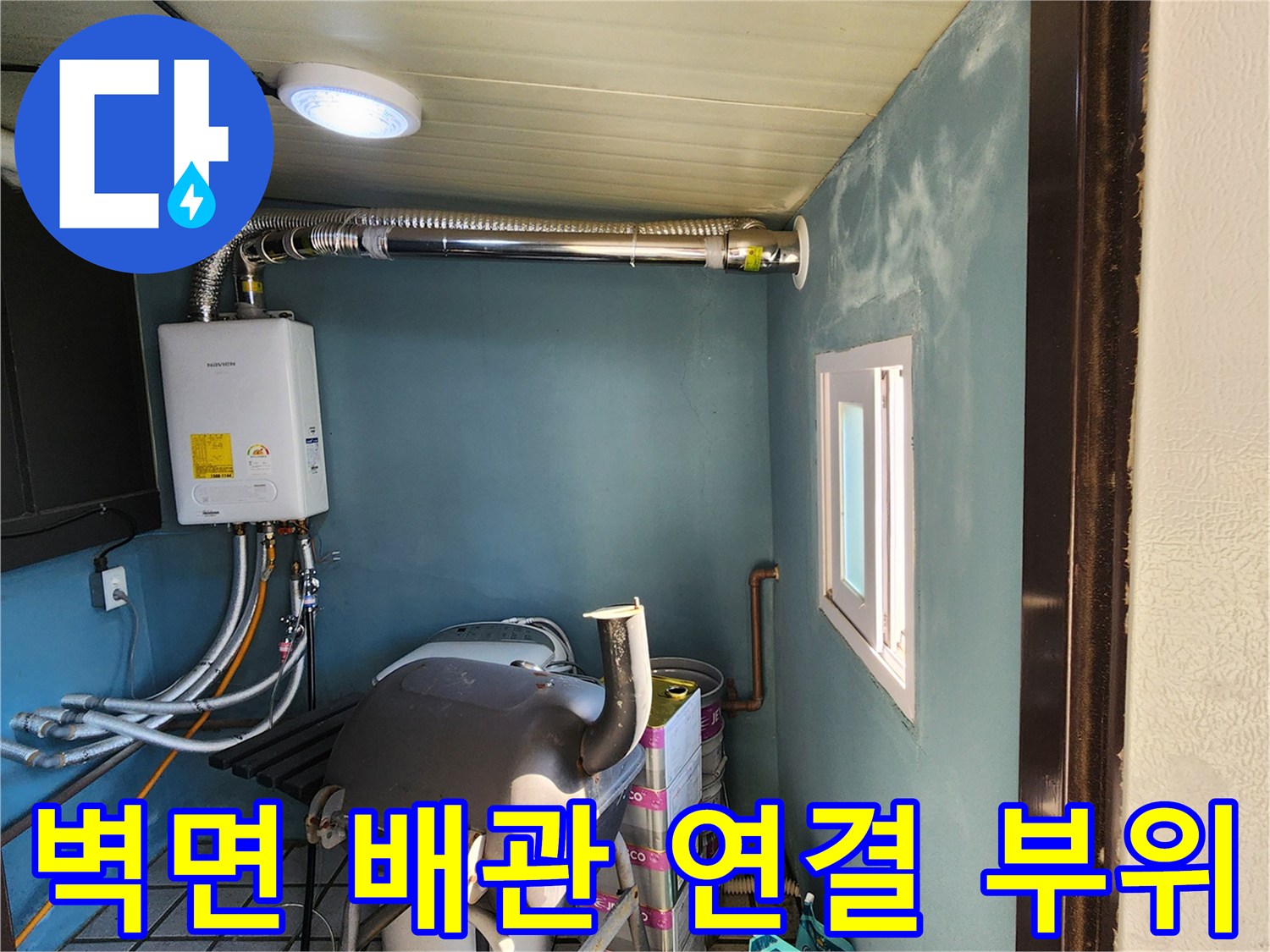 흰색 장비와 은색 배관이 벽면에 설치된 다용도실 내부 전경