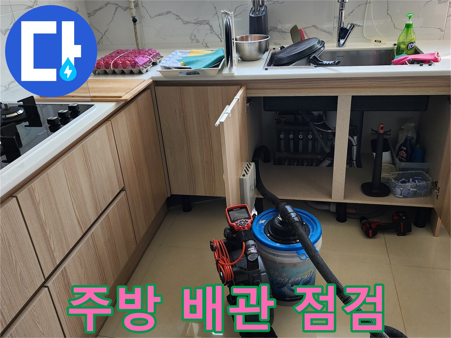 싱크대 아래쪽 공간에 놓인 진단 장비와 노출된 배관의 상태를 보여주는 사진