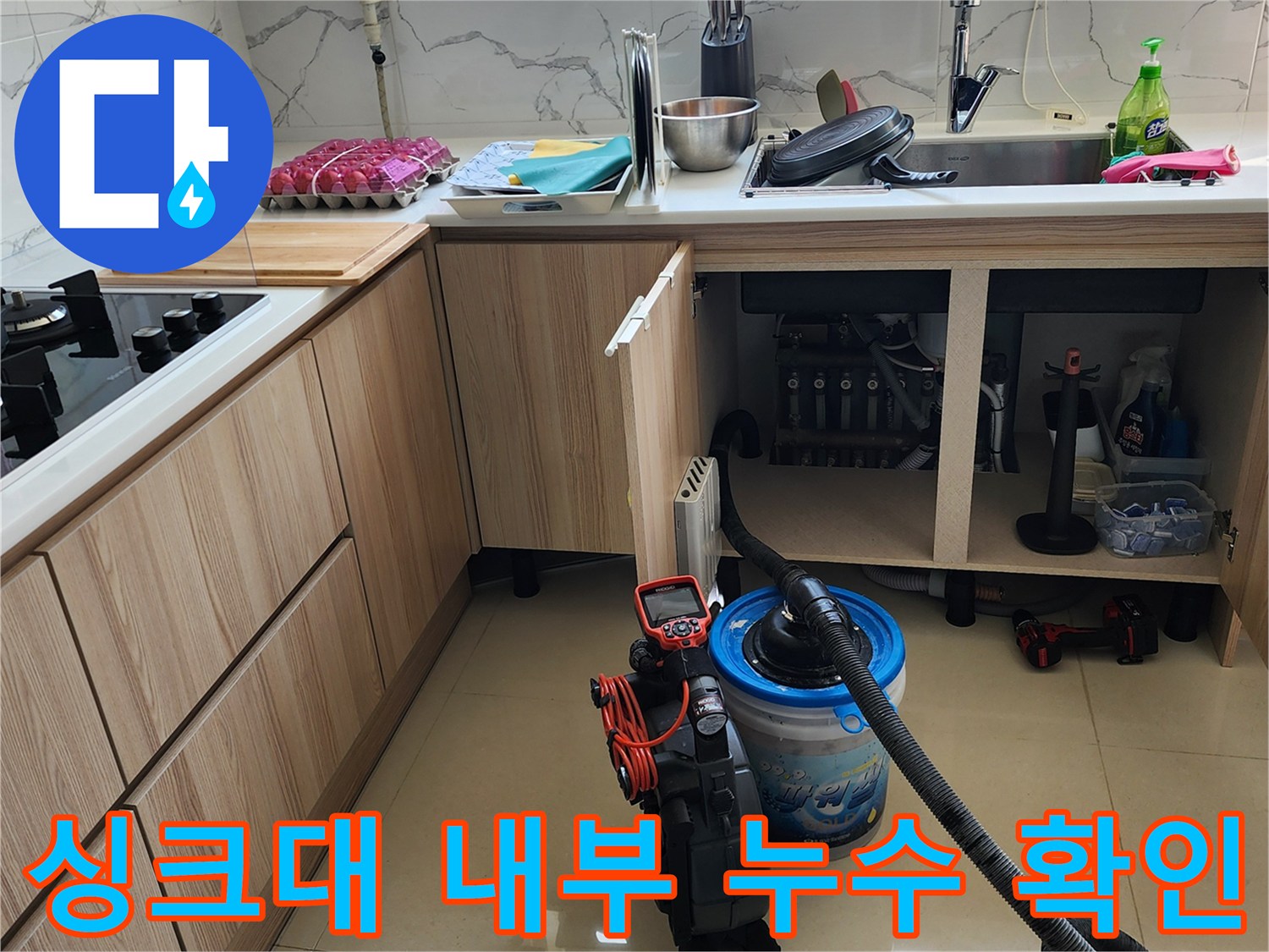 싱크대 하부장 내부에 고인 물과 배관의 노후 상태를 점검하는 작업입니다.
