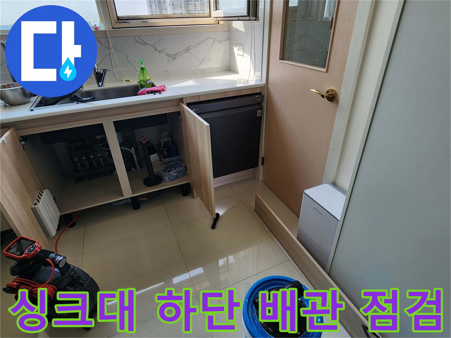 싱크대 하부장 내부의 배관 연결 부위를 육안으로 검사하는 모습입니다.