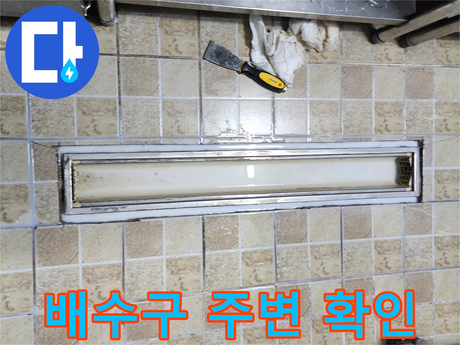 금속 트렌치 구조물과 타일 접합부의 누수 징후를 보여주는 사진입니다.