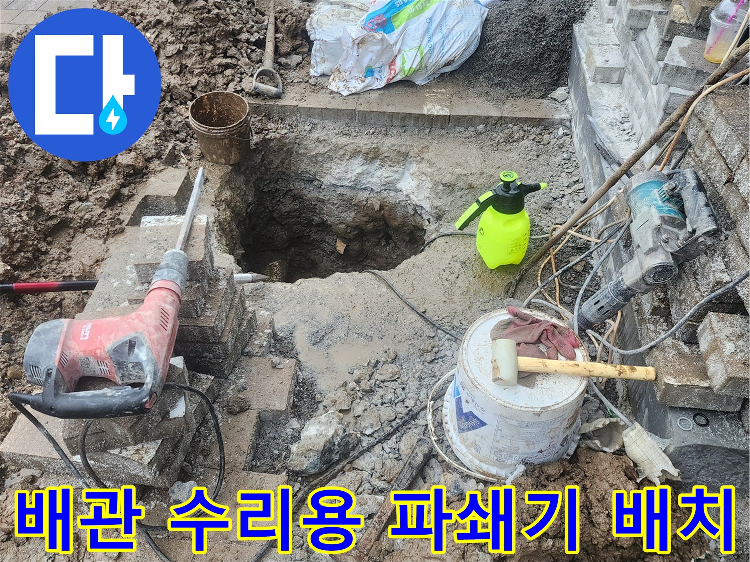 공사 현장에 놓인-전동 파쇄기와 작업 도구 및 굴착된 지면의 모습입니다.