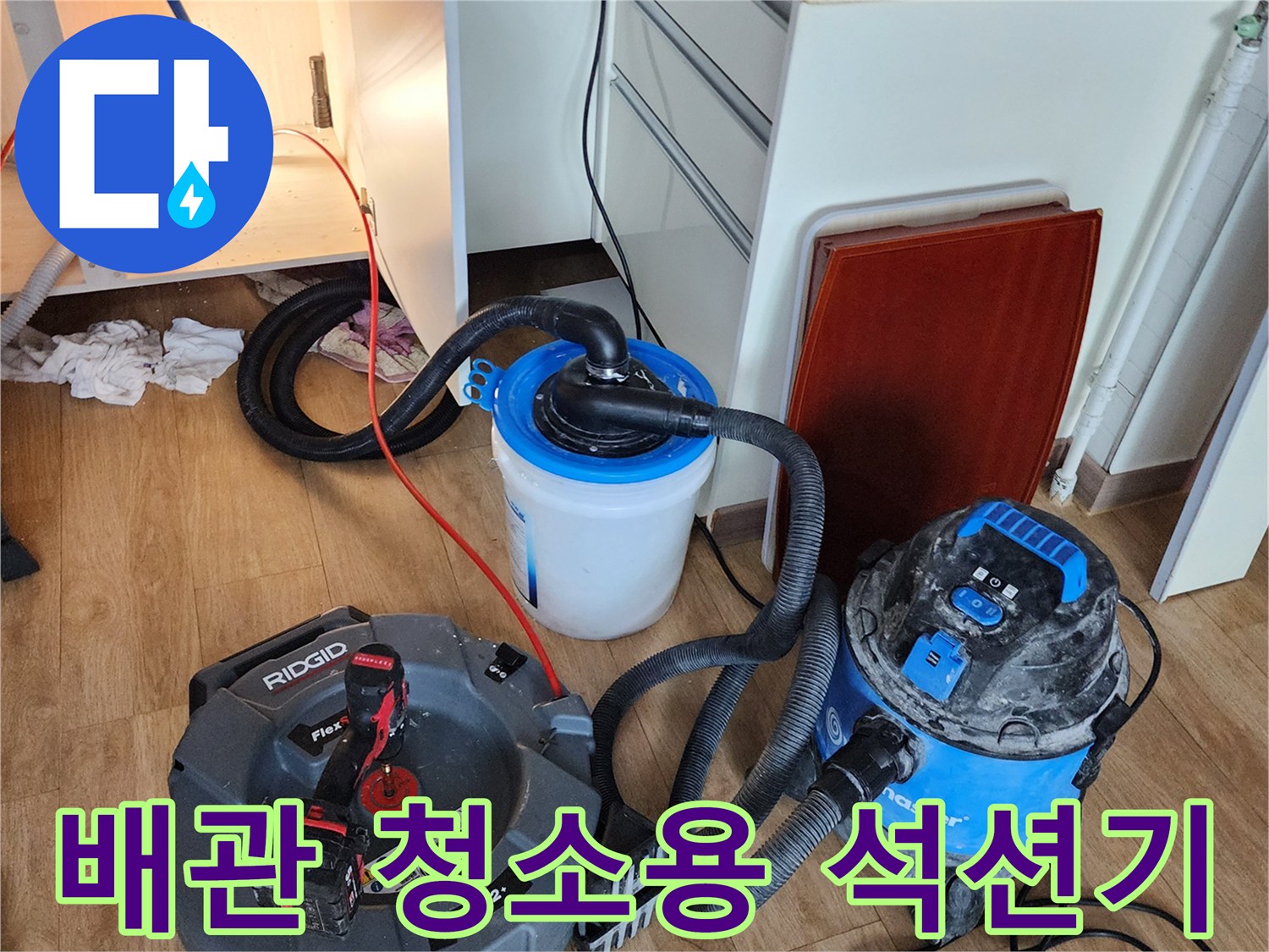 싱크대 아래 배관 청소를 위해 배치된 전문 흡입 장비와 호스