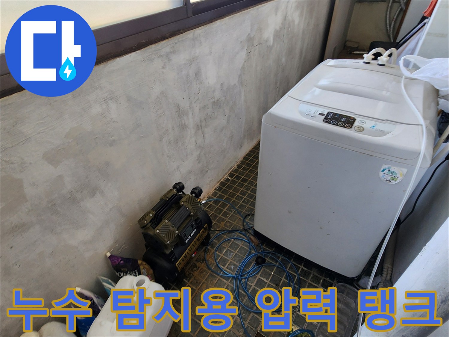 바닥에 설치된 검정색 공압 테스트 장비와 연결된 파란색 호스