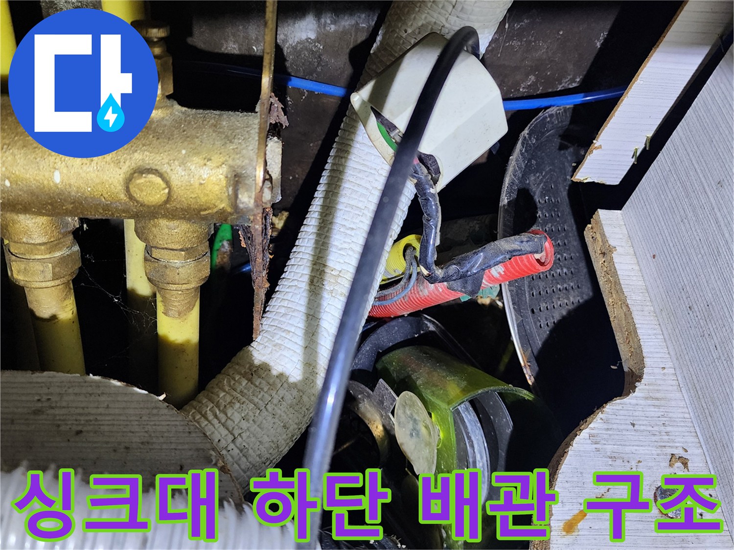싱크대 아래 금속 급수관과 흰색 주름관이 위치한 모습