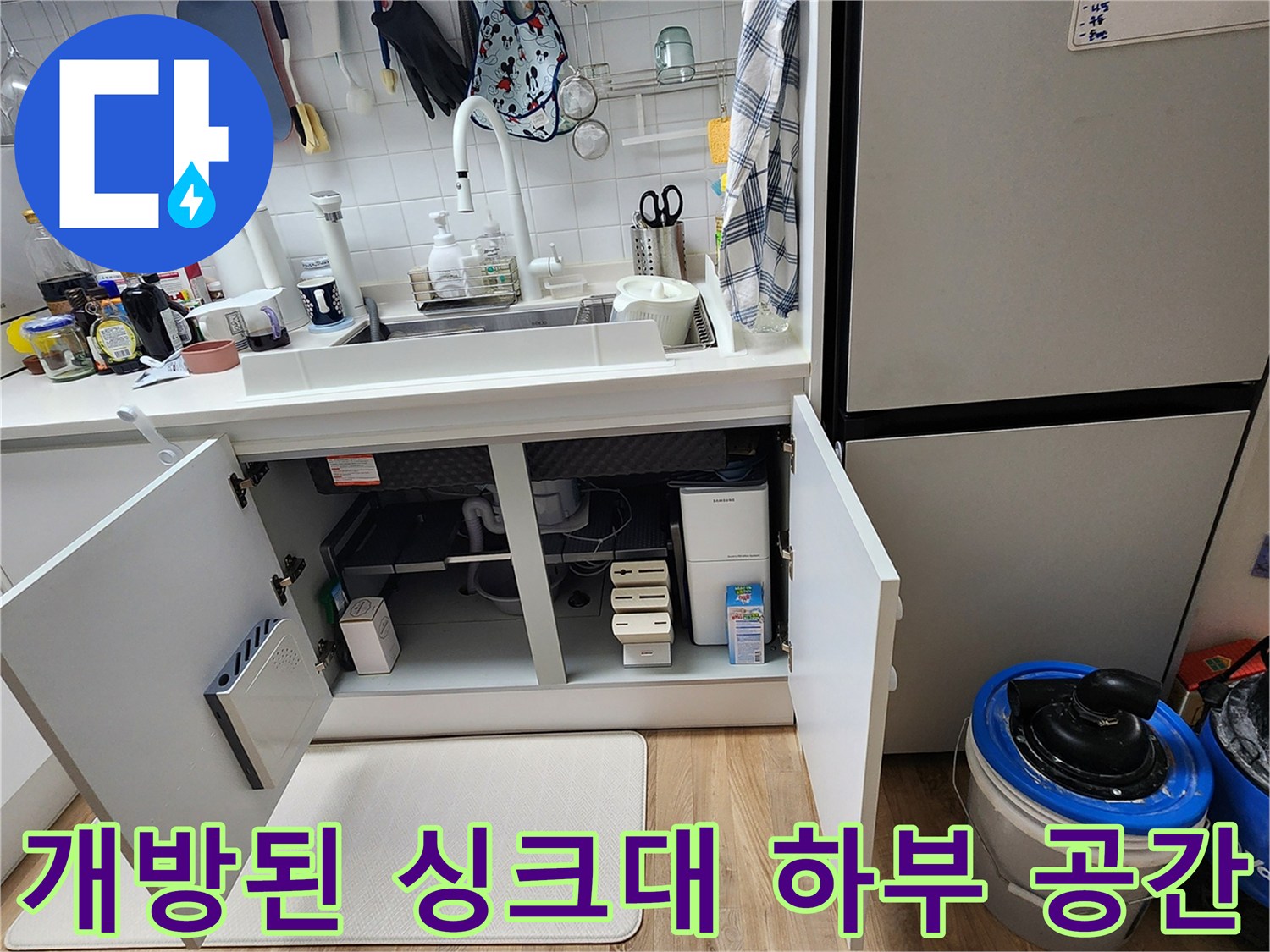 싱크대 아래쪽 하부장을 열어 내부 배관과 바닥 상태를 점검하는 현장 사진