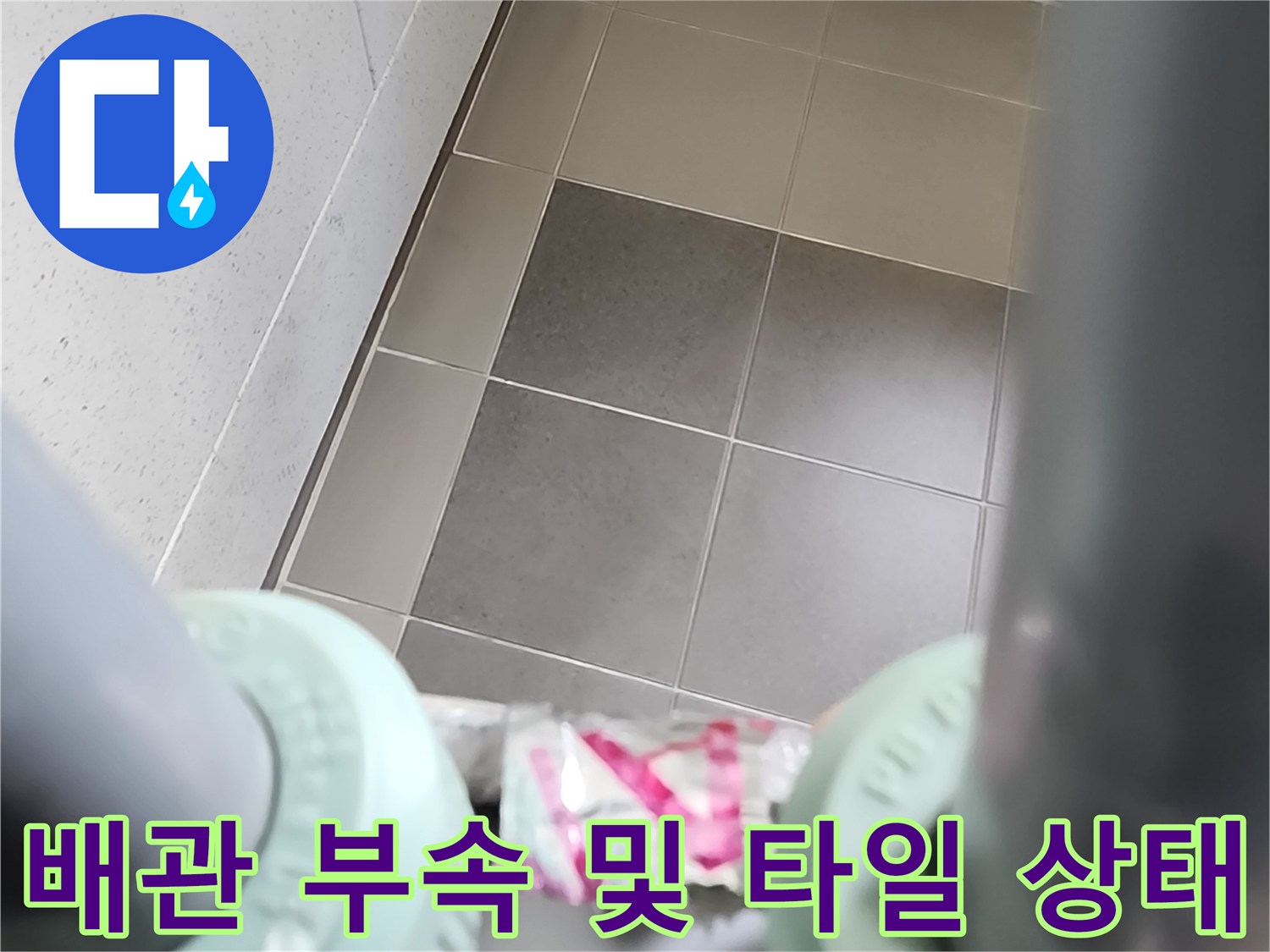 싱크대 하부-배관 연결용 흰색 부품과 주변 타일 벽면