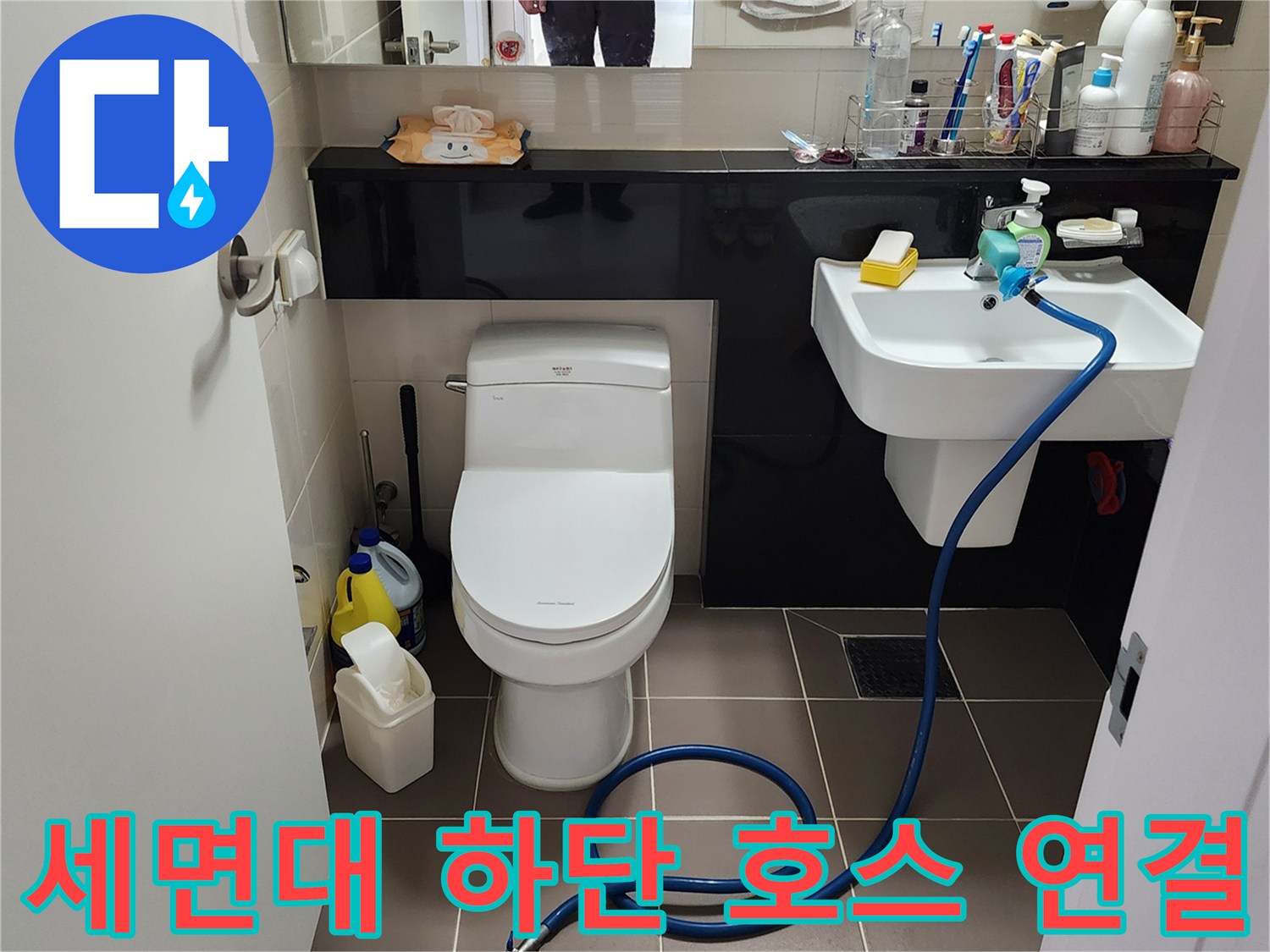 욕실 세면대 아래로 뻗어 있는 파란색 점검용 호스와 배관 상태