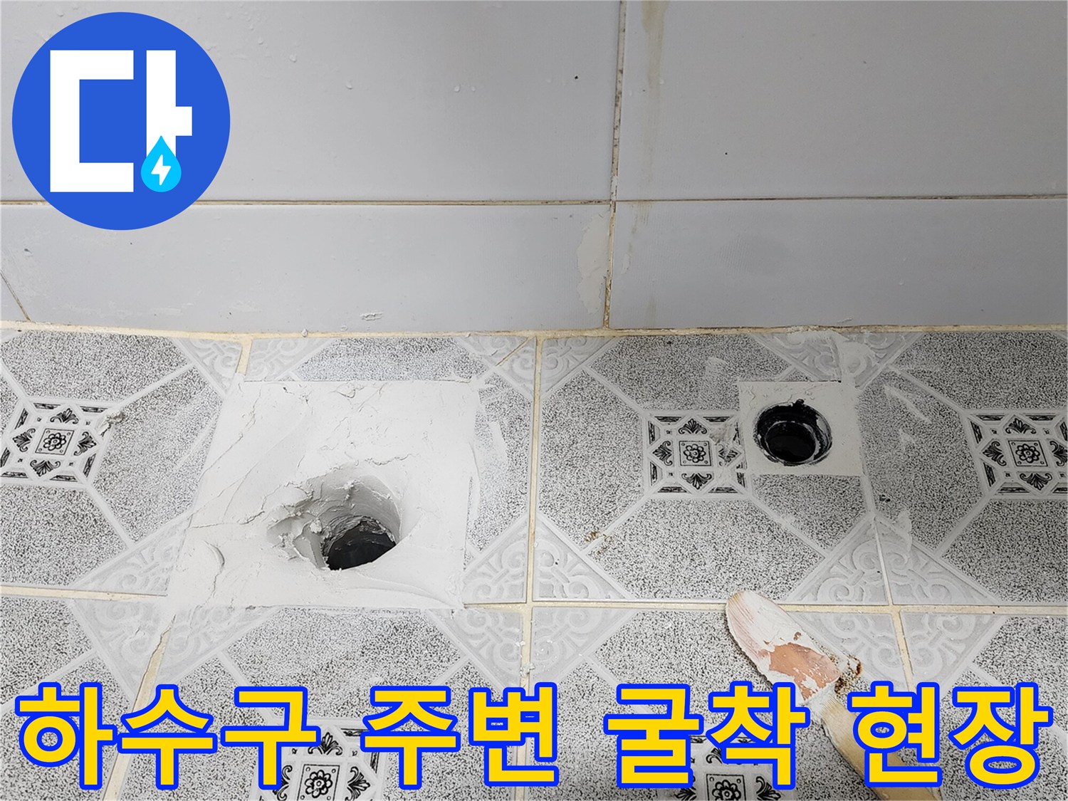 배수구 입구 옆 타일을 제거하고 내부 배관을 드러낸 작업 사진입니다.