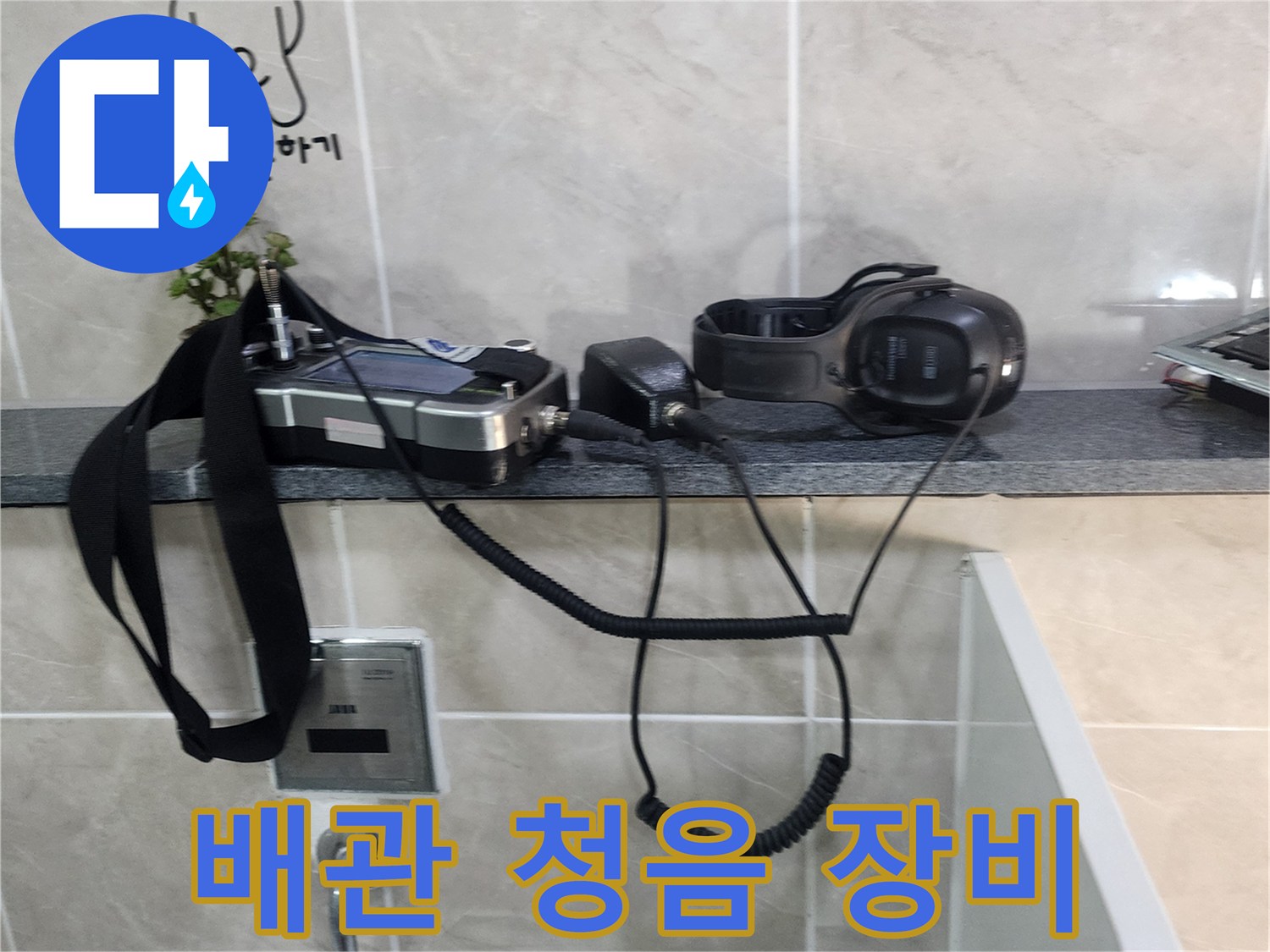 화장실 타일 벽면에 놓인 전문 배관 탐지용 헤드셋과 기기