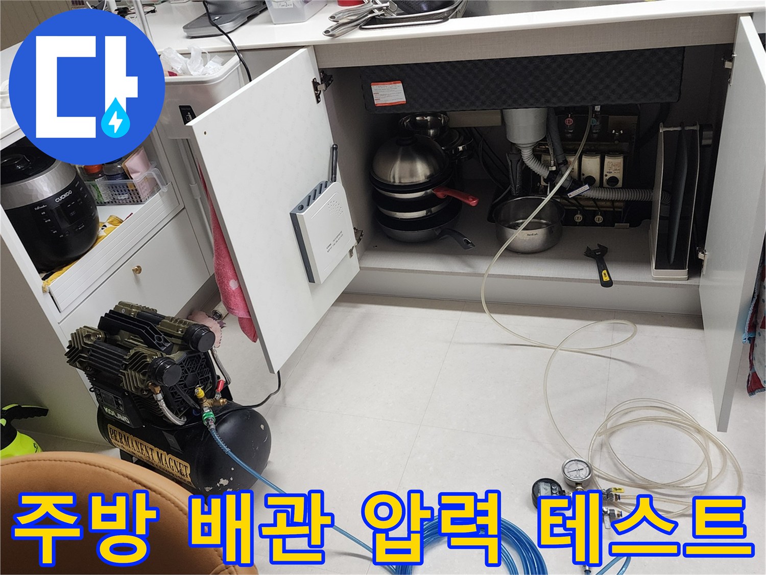 싱크대 하부 배관에 연결된 공압 장비와 게이지의 모습