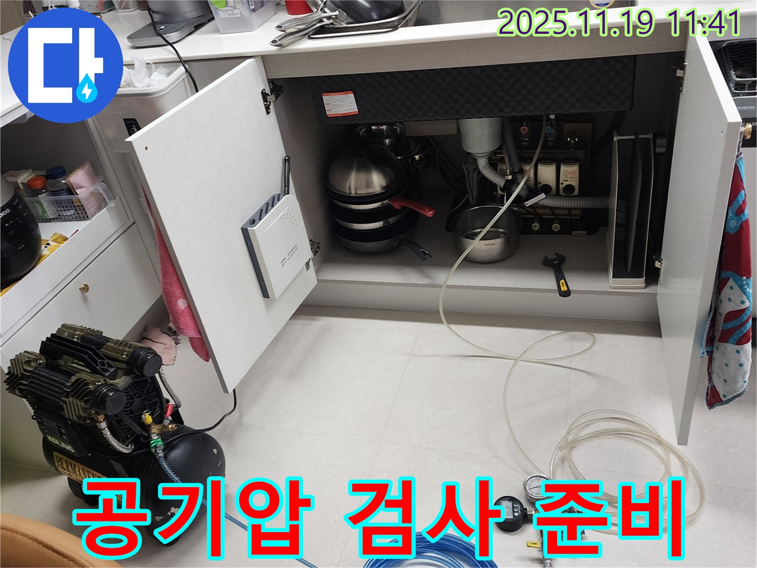 포천시 내촌면 마명리 누수 현장 - 싱크대 하부에서 공기압 검사를 준비하는 모습입니다. 꼼꼼하게 장비를 살펴보고 있습니다.