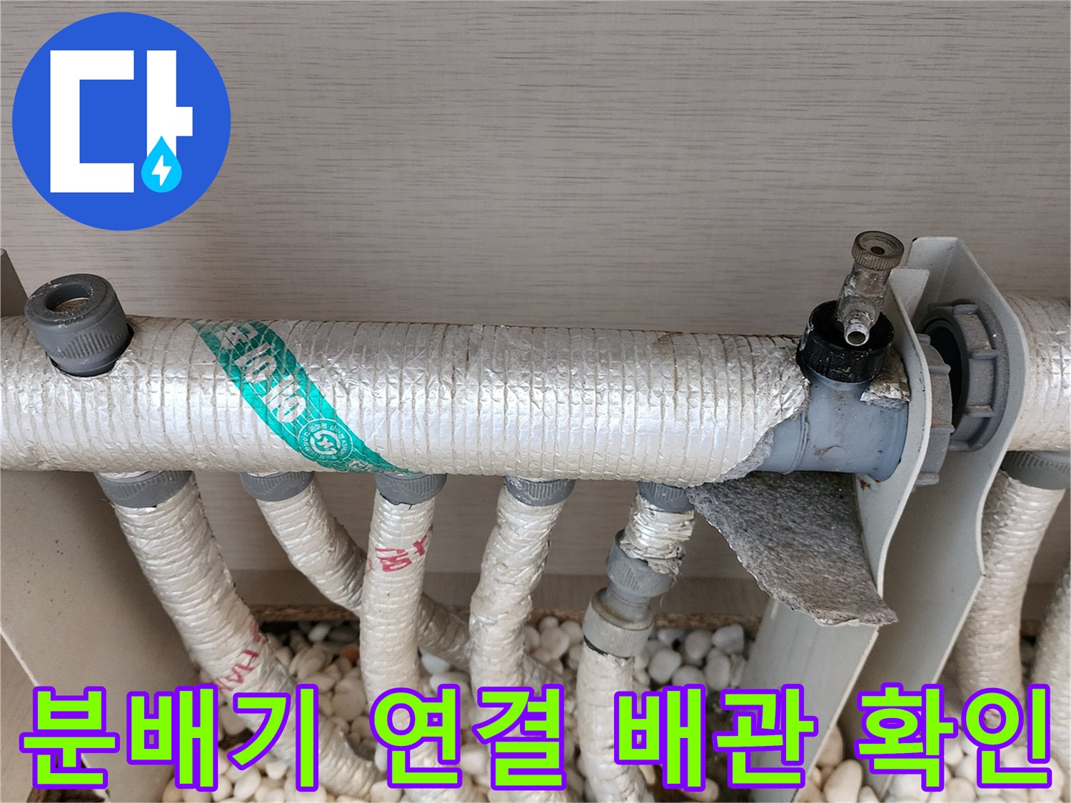 흰색 자갈과 은박 보온재가 씌워진 배관의 교차 지점