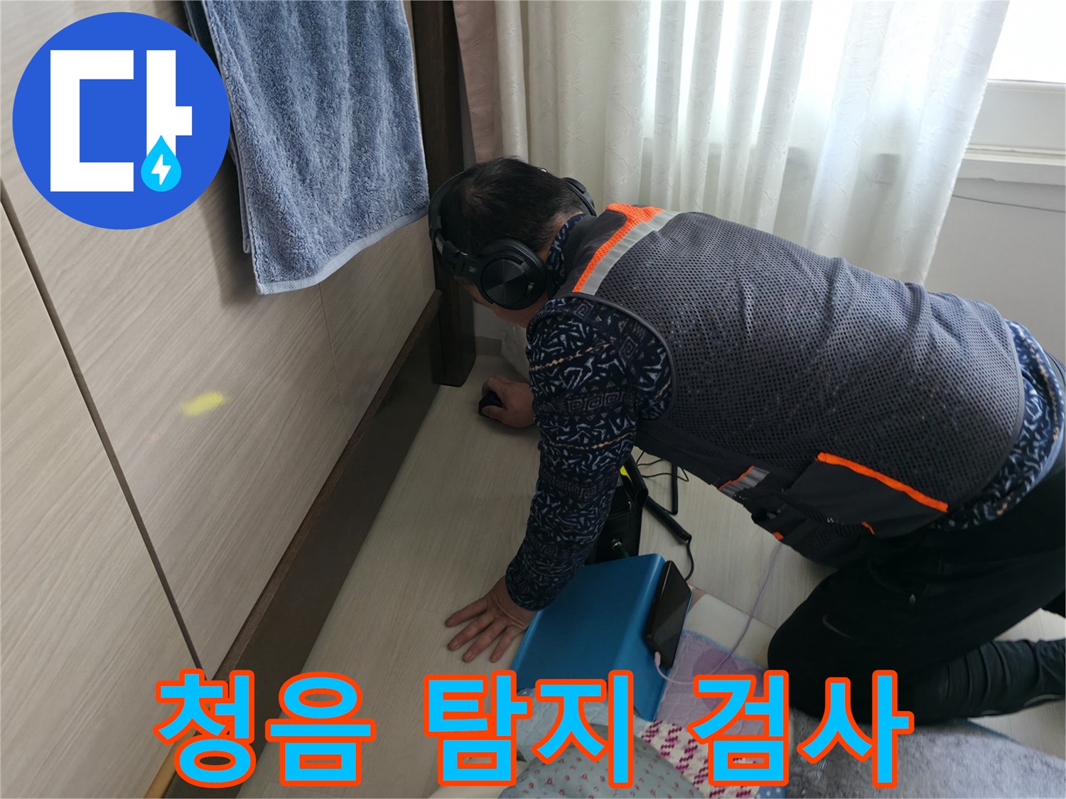 누수 전문가가 - 헤드폰을 착용하고 - 청음 탐지기로 누수음을 듣고 있는 모습