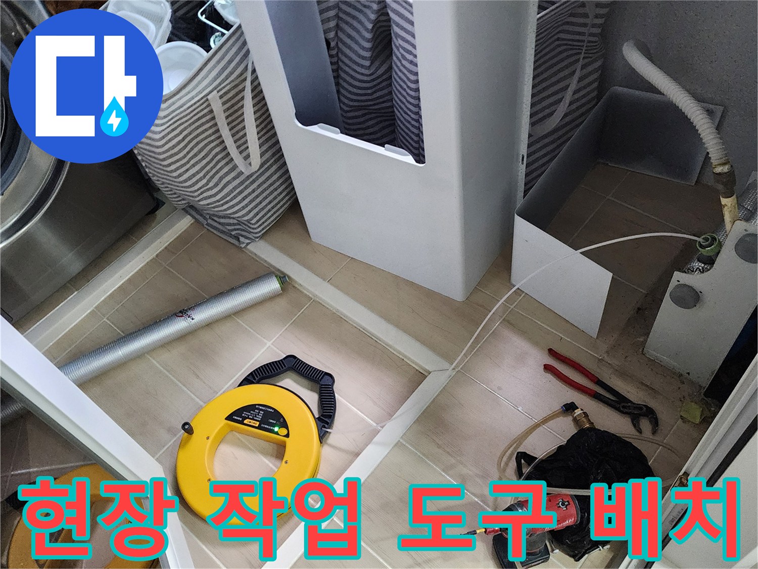 가스 탐지 릴과 전동 드릴이 놓여 있는 세탁기 아래 점검 공간