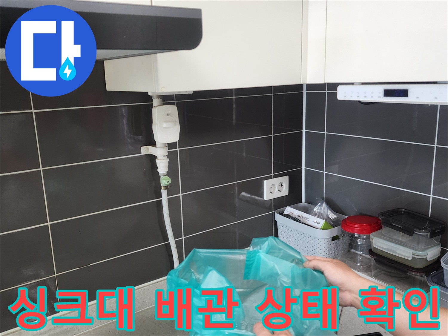 싱크대 하부장 내부의 급수 밸브와 연결된 호스 부위를 조사하고 있습니다.