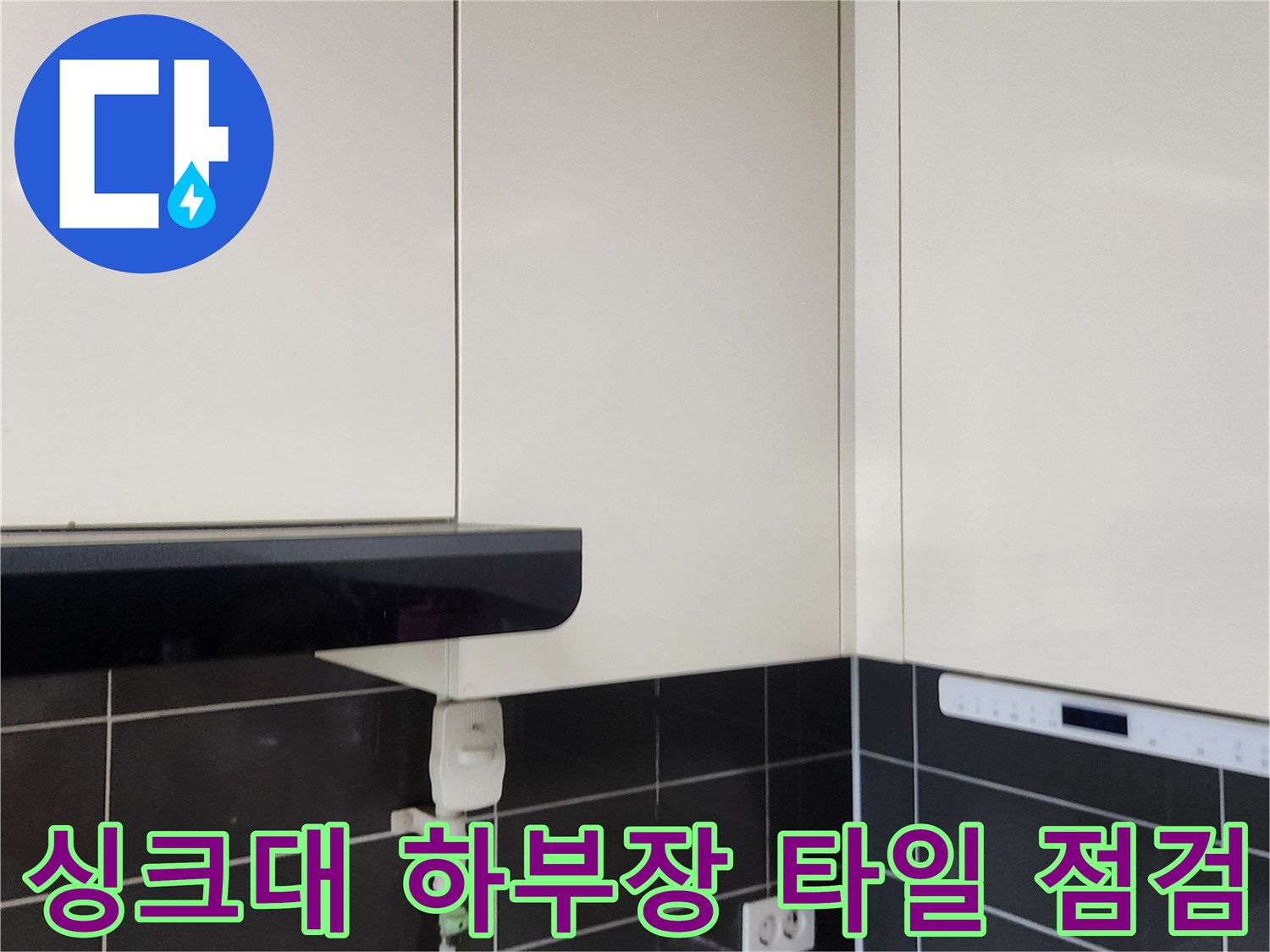 주방 싱크대 아래쪽 타일 벽면과 전기 콘센트 부위 상세 촬영