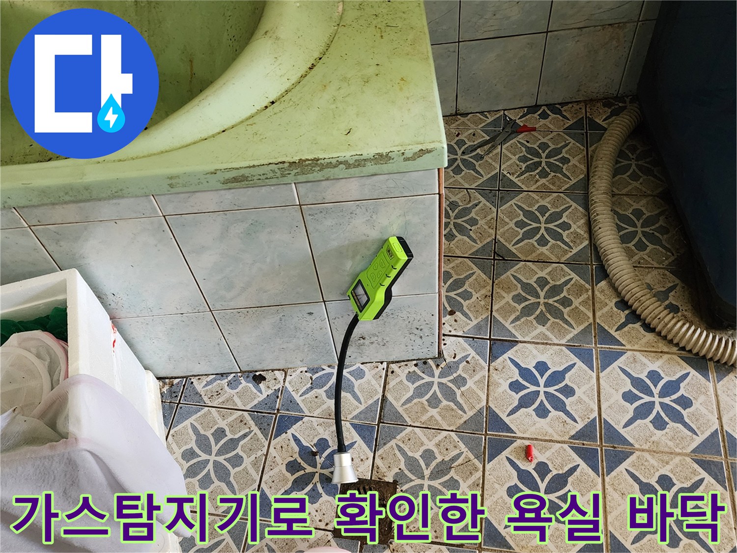 욕실 타일 바닥에서 가스 탐지기를 사용하여 누수 지점을 찾는 모습