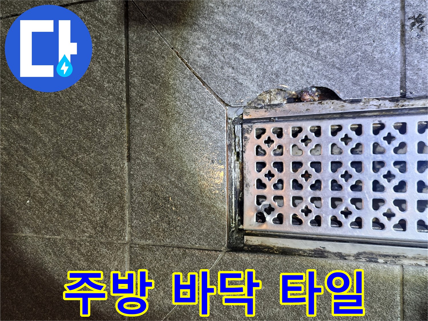 어두운 회색 타일과 금속 배수구의 접합부 사진