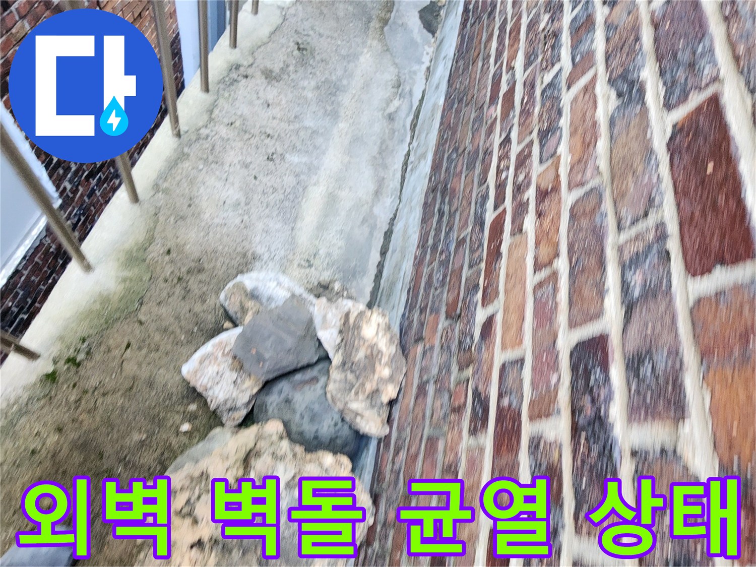 붉은색 벽돌 구조물 아래쪽의 갈라진 틈새와 거친 지면 상태를 보여주는 이미지
