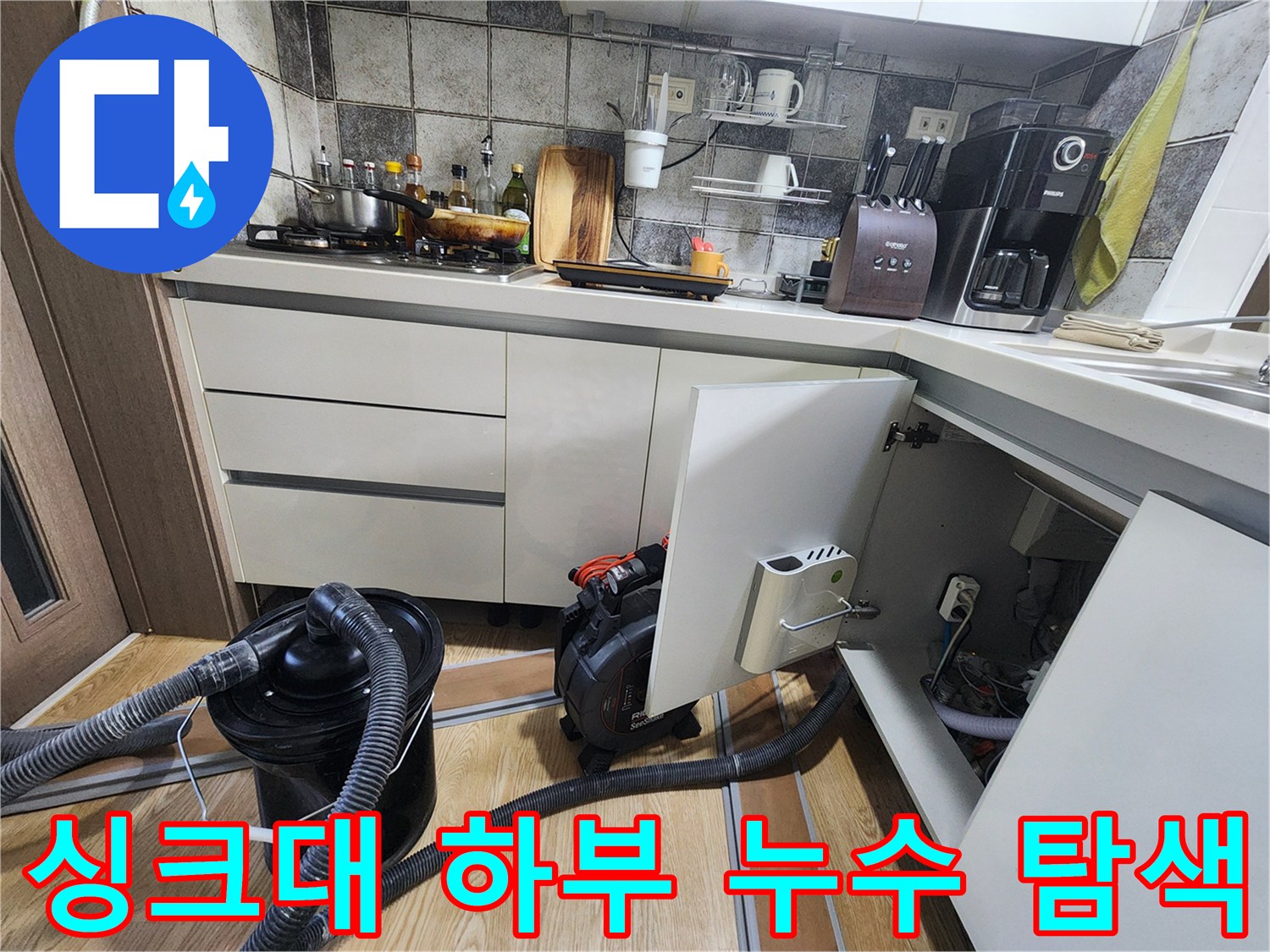 싱크대 밑 공간에 설치된 점검용 장비와 연결 호스 사진입니다.