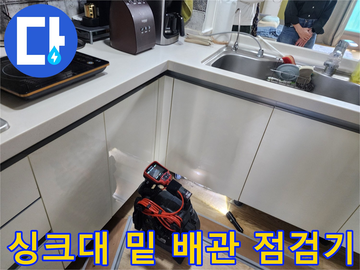 주방 싱크대 아래 공간에서 작업 중인 배관 탐지 장비 세트