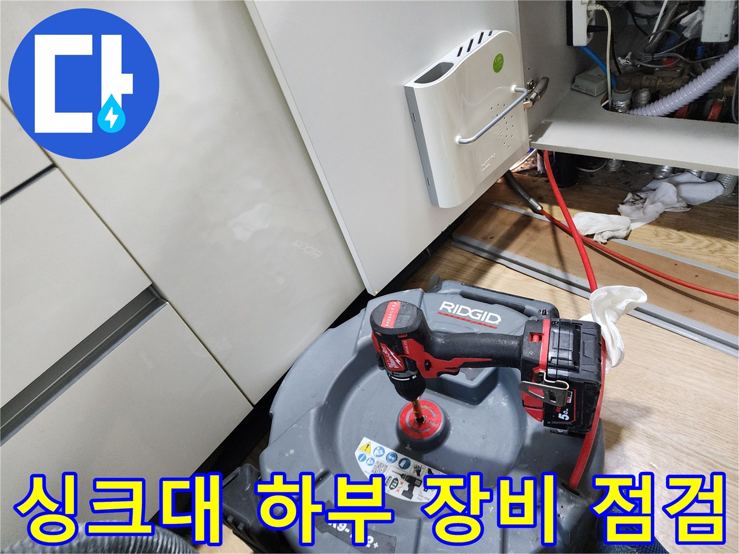 주방 싱크대 하부 공간에 놓인 배관 탐지용 드릴과 장비들