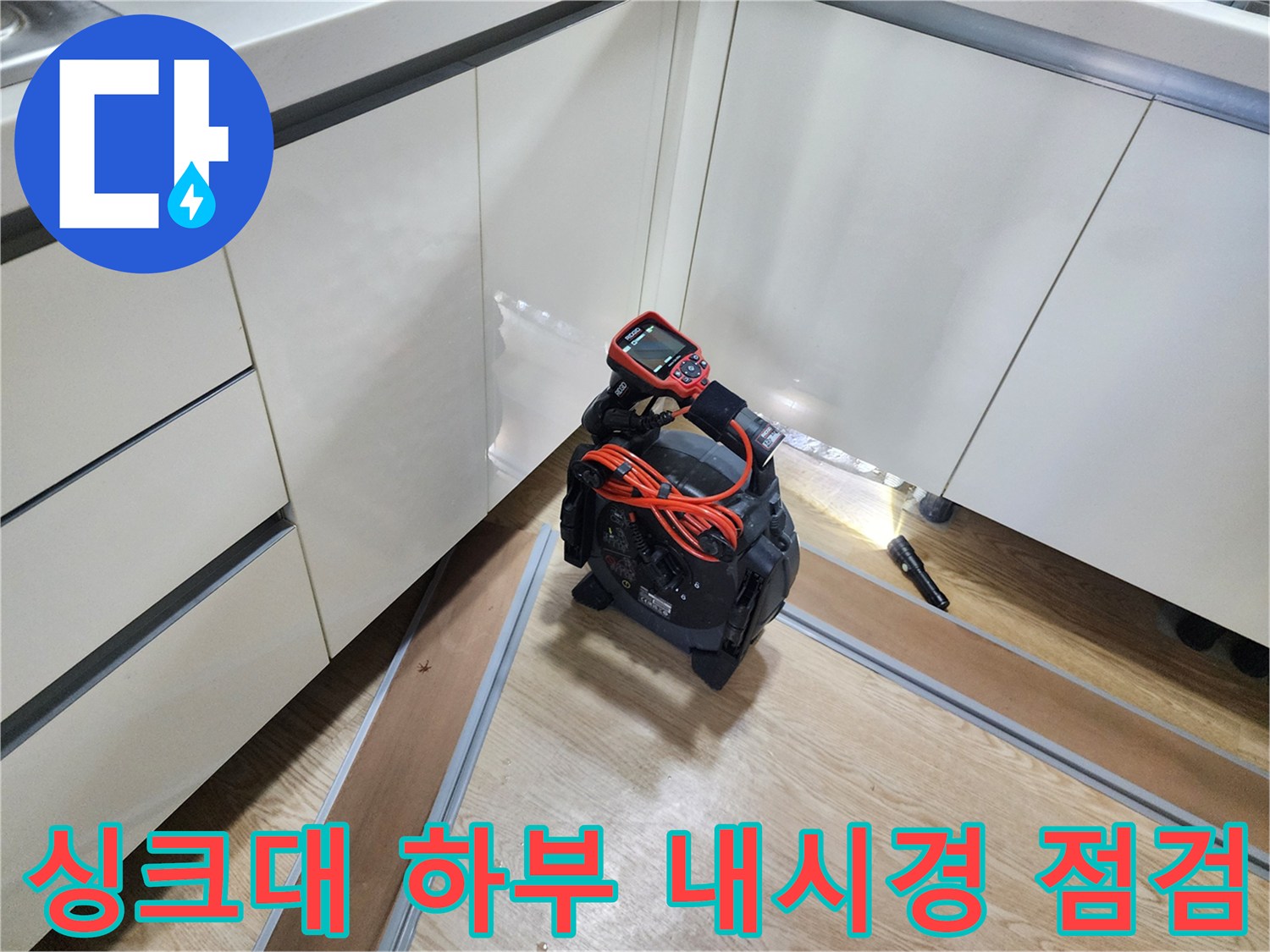 주방 싱크대 하부 공간에서 배관 상태를 확인하기 위해 내시경 카메라를 사용하는 모습