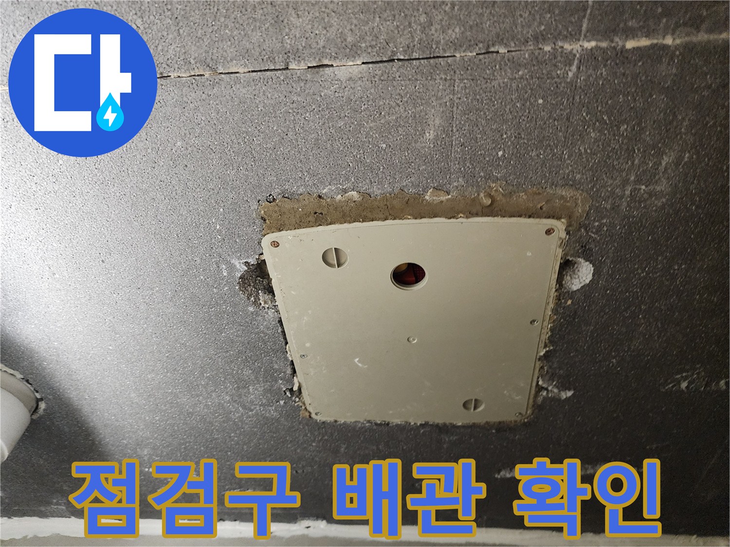 점검구 내부의 전기 박스와 배관 부위를 촬영한 사진입니다.