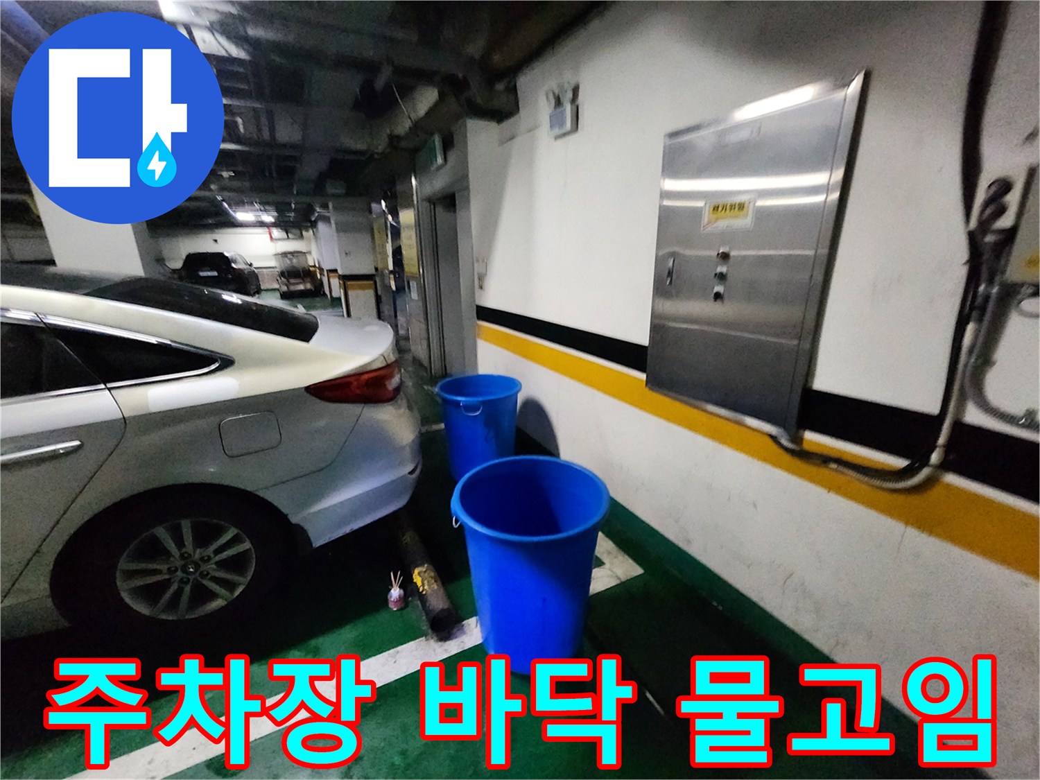 지하 주차장 벽면 아래에 파란색 양동이가 놓여 있는 모습