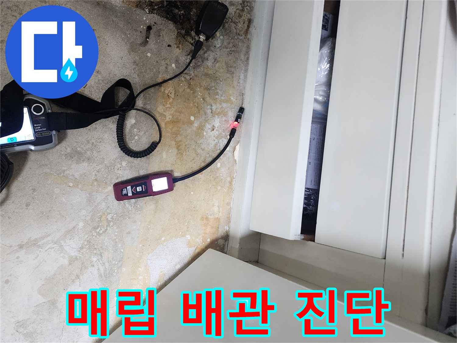 가구 아래 젖은 바닥과 연결된 가스 탐지 장비의 모습
