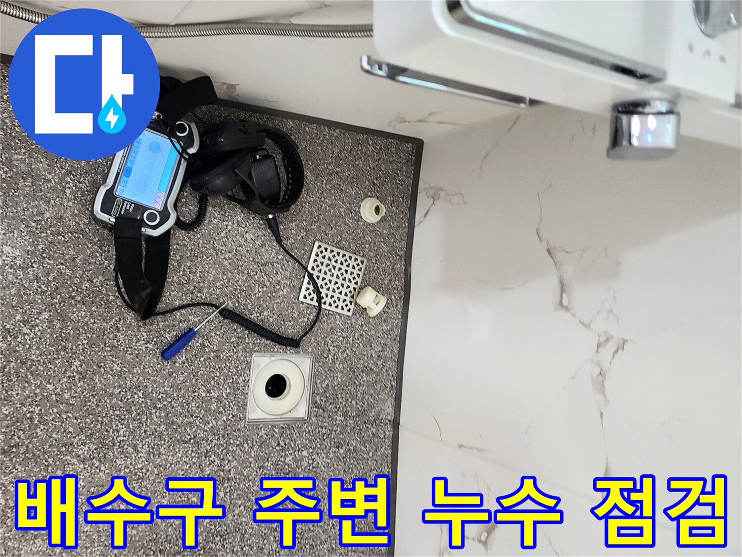 탈거된 배수구 부속과 탐지기가 바닥에 놓여 있는 현장 사진입니다.