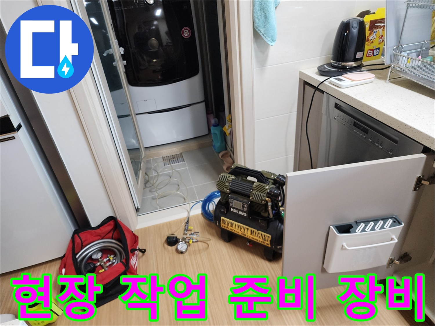 싱크대 아래 배관 작업을 위해 배치된 컴프레셔와 각종 공구들