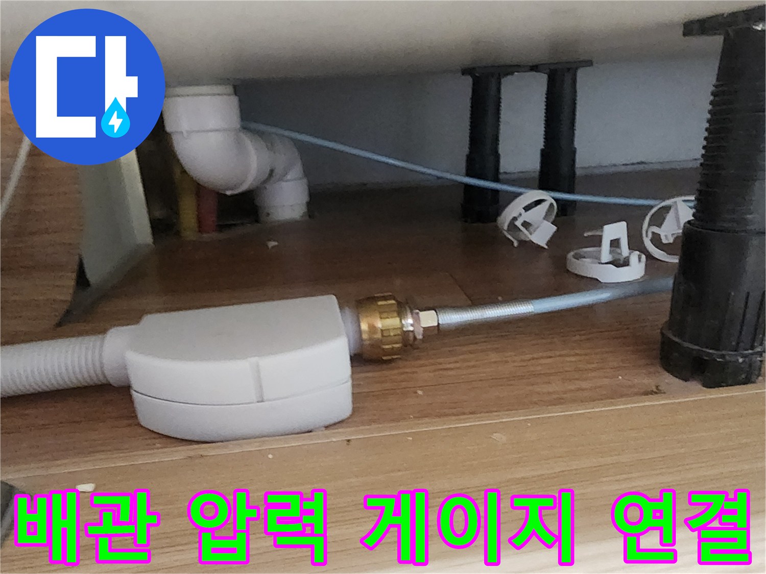 싱크대 아래 흰색 배관과 테스트용 압력 장치 연결 부위