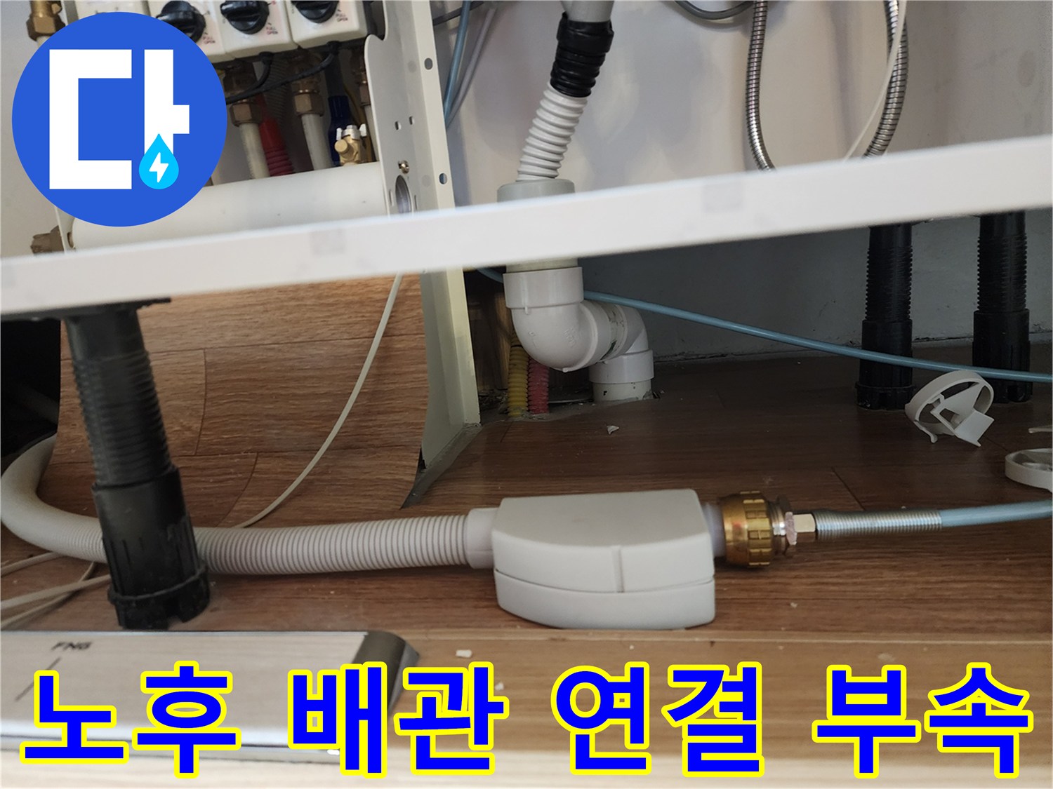 싱크대 아래쪽의 흰색 플라스틱 배관과 금속 너트 부위
