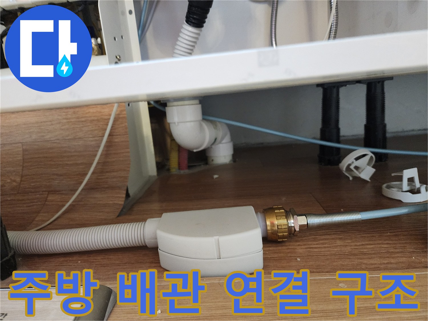 싱크대 하단 바닥의 흰색 주름 호스와 금속 배관 부품 근접 촬영