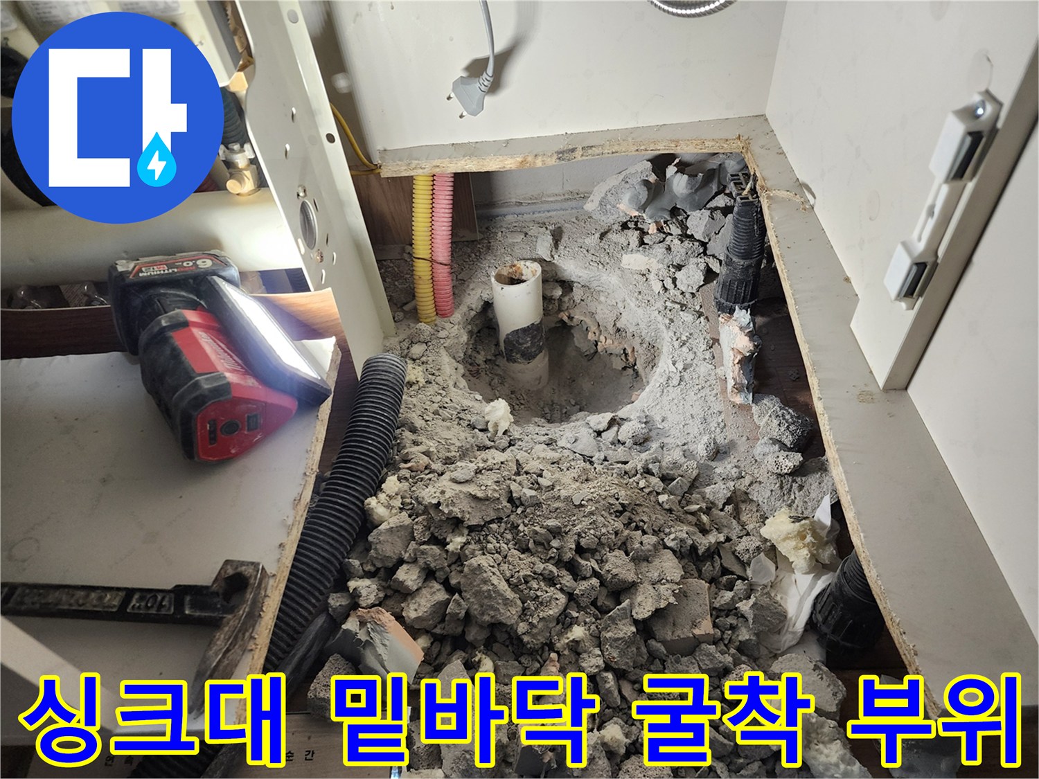 주방 싱크대 아래쪽을 파내어 노출시킨 매립 배관과 주변 파쇄된 흙들
