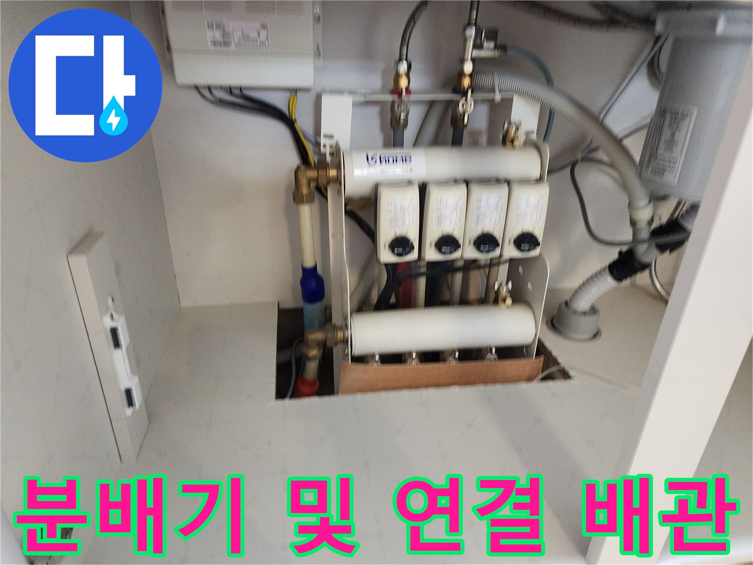 주방 하부장 내부의 수도 분배기와 여러 갈래의 급수 배관