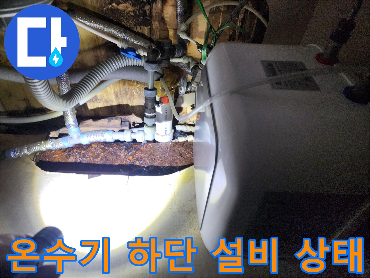 전기 온수기 아래쪽 복잡한 배관과 부식된 금속 부품 사진
