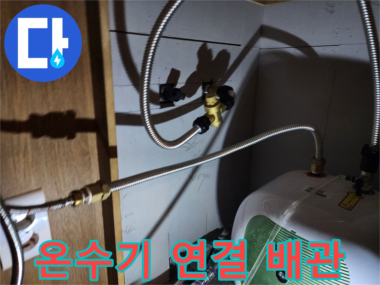 주방 싱크대 하부장 내 설치된 전기 온수기와 금속 플렉시블 호스 연결 상태