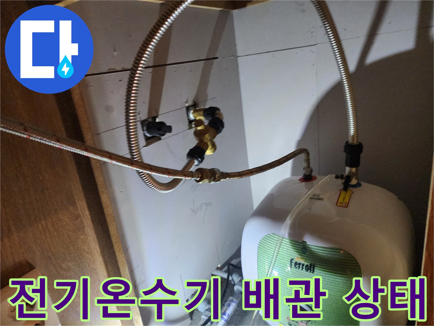 주방 싱크대 하부장에 설치된 전기 온수기와 연결 배관 모습