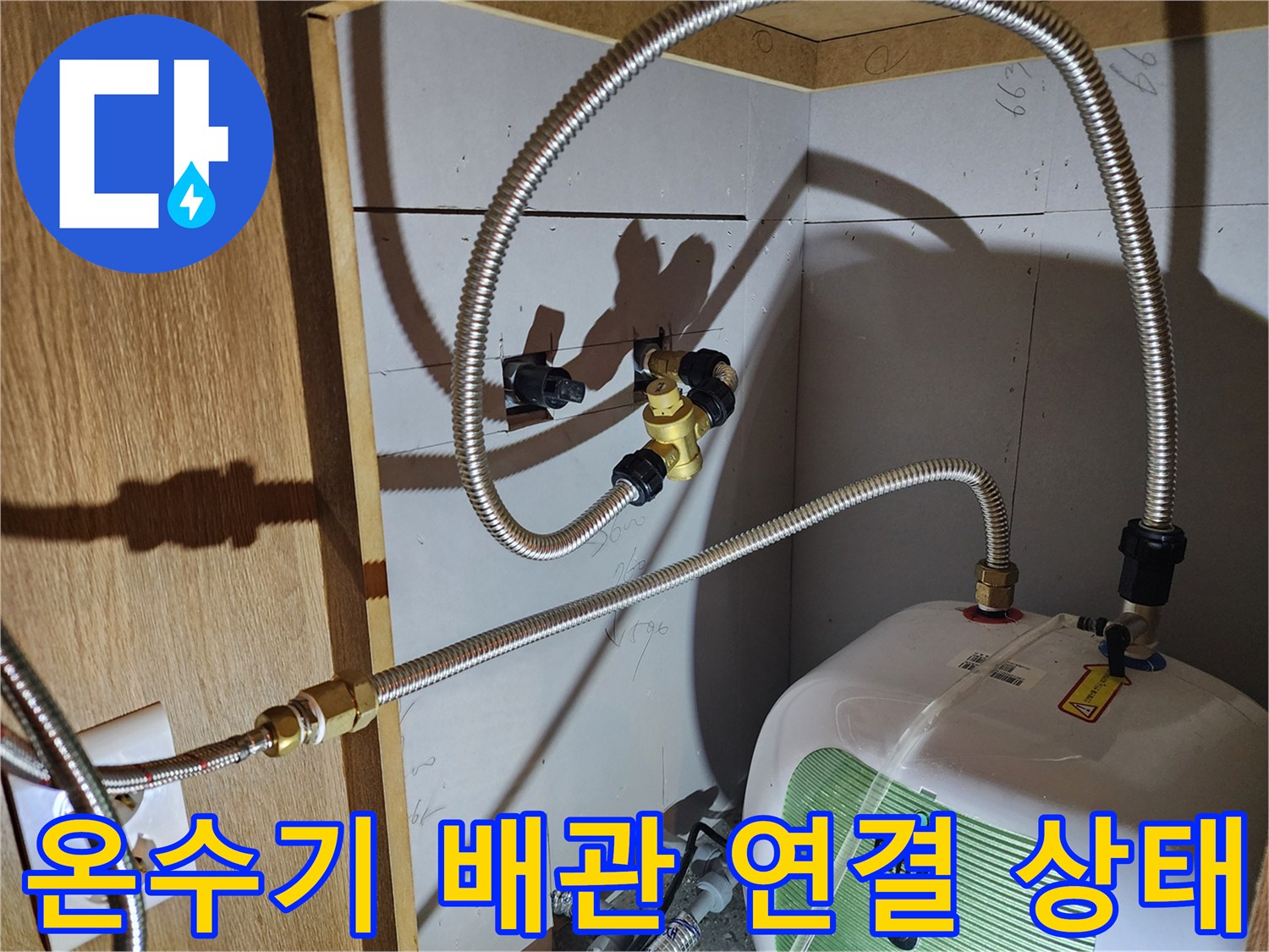 주방 하부장 내 설치된 전기 온수기와 금속 플렉시/스블 호스 연결 부위 모습