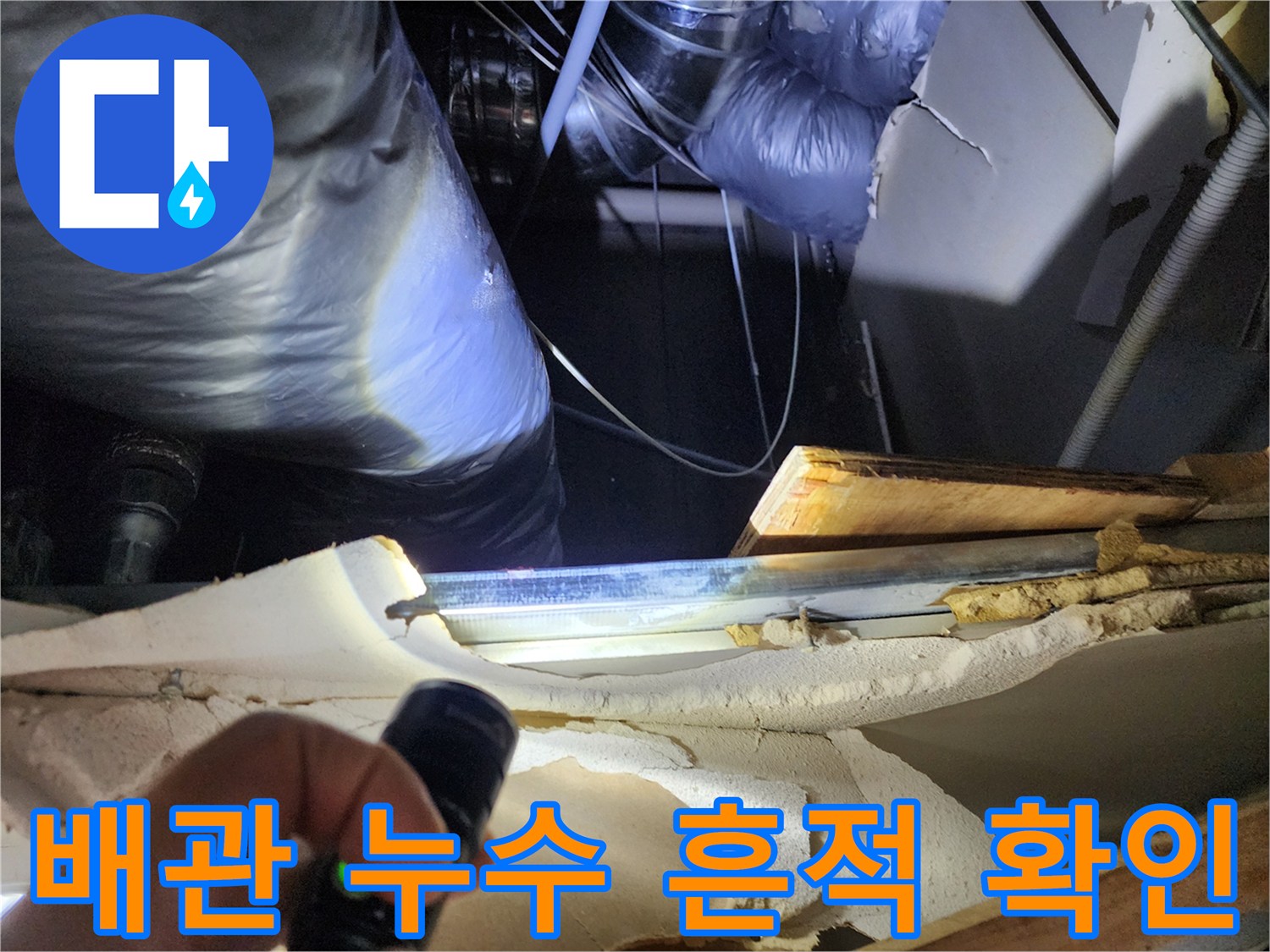 손전등으로 비춘 싱크대 하부 배관의 습한 상태와 주변 구조물