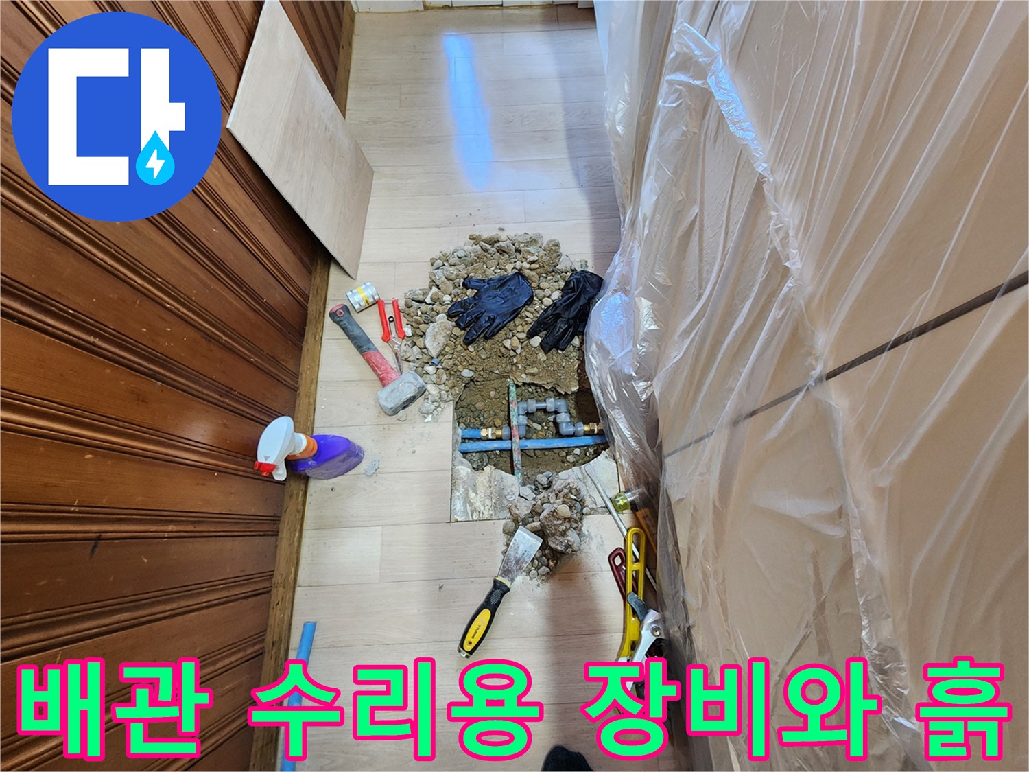공사 중인 바닥 현장에 놓인 작업 도구들과 파헤쳐진 배관 부위입니다.