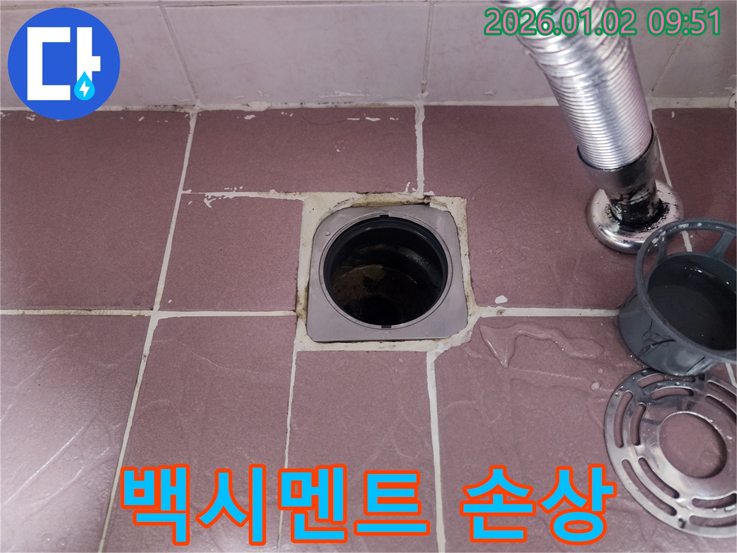 욕실 배수구 주변 백시멘트 손상 - 백시멘트의 균열이나 탈락이 누수의 원인이 될 수 있음을 보여주는 사진입니다.
