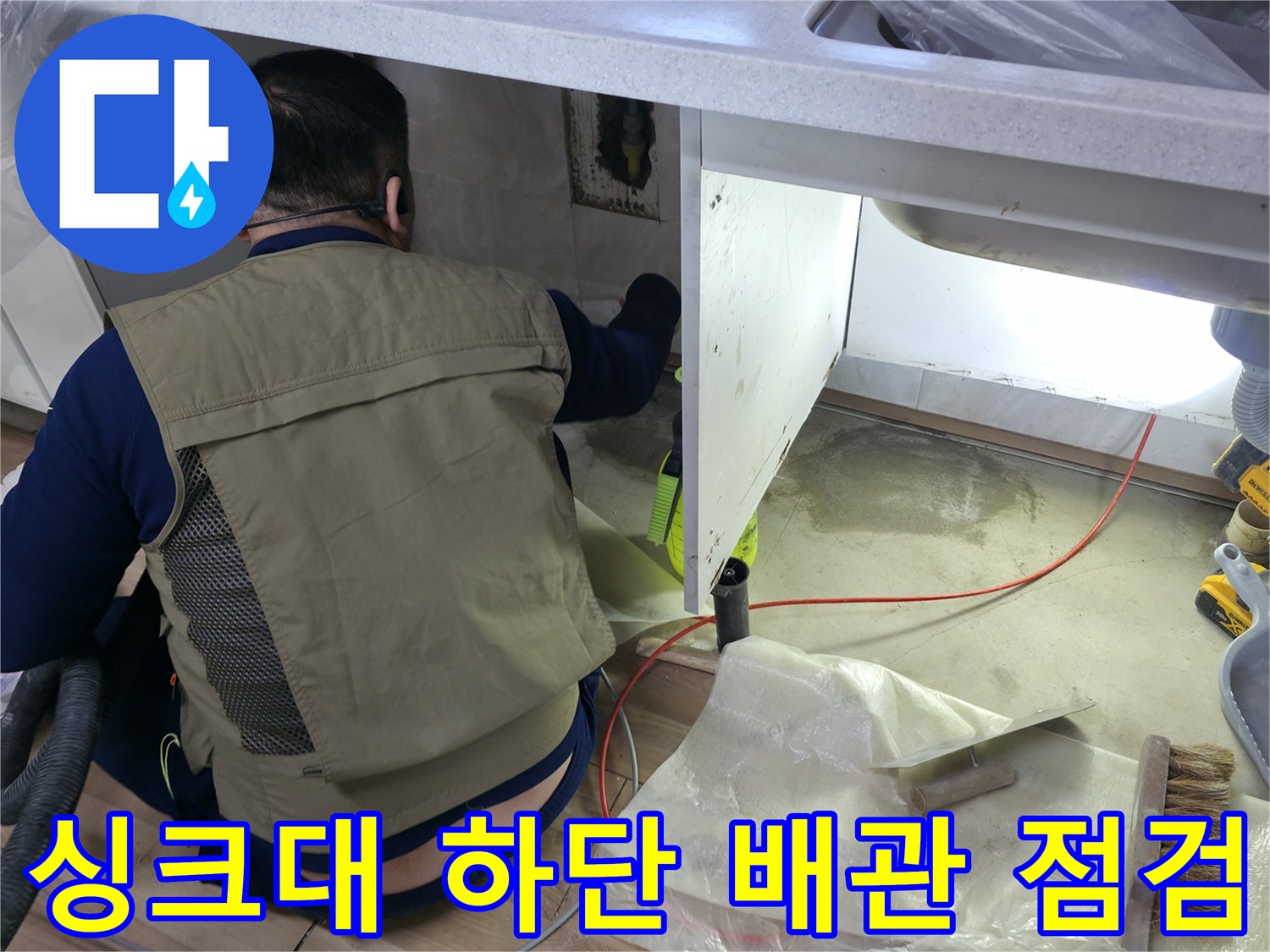 싱크대 밑 공간에서 누수 지점을 찾기 위해 배관 주변을 조사하는 모습입니다.
