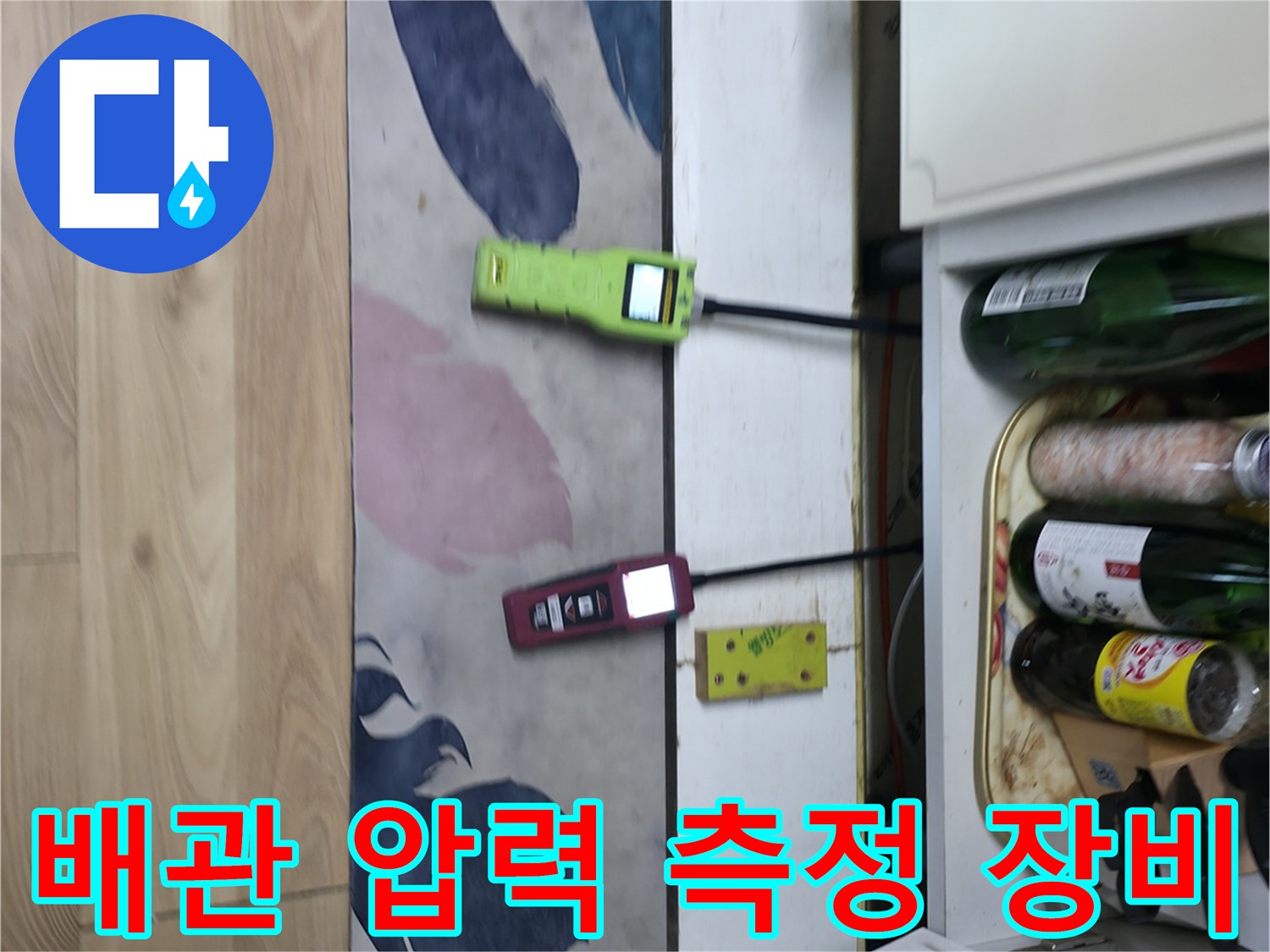 싱크대 하부장 근처에서 진행 중인 배관 압력 측정 및 가스 탐지 작업
