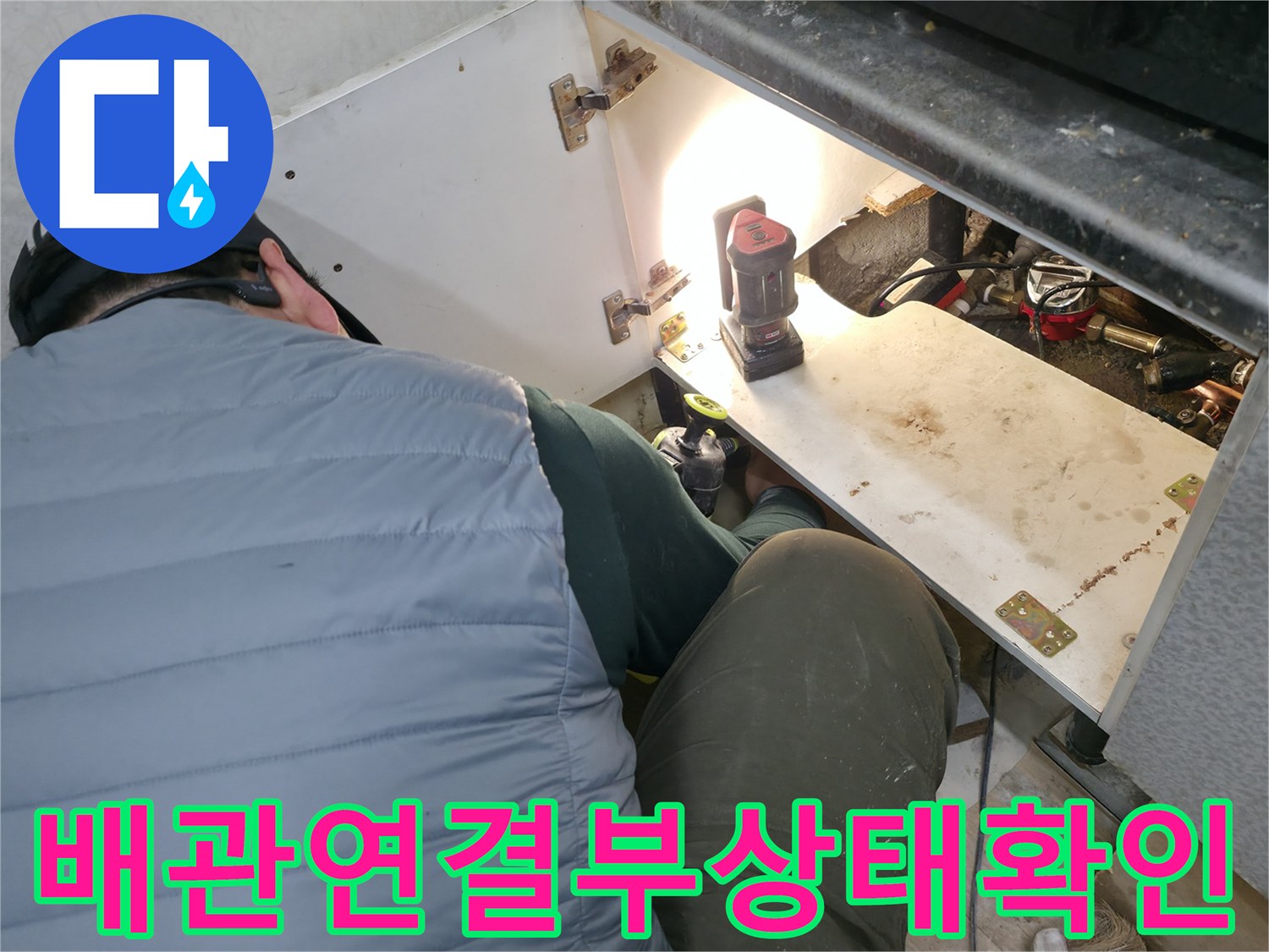하부장-안쪽-배관-연결-부위를-조명으로-비추어-보는-작업