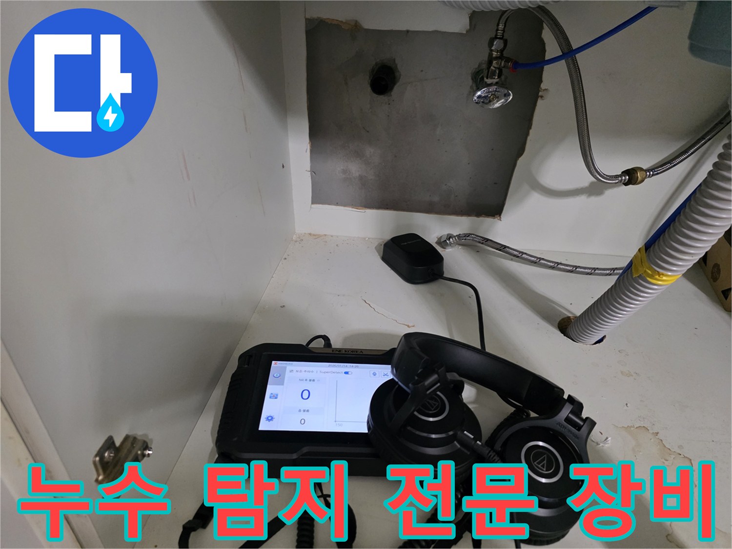 배관 압력 측정 중인 디지털 기기와 청음용 헤드셋-싱크대 하단 작업
